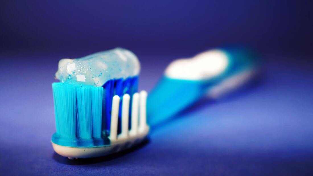 toothbrush with whitening toothpaste on a blue surface